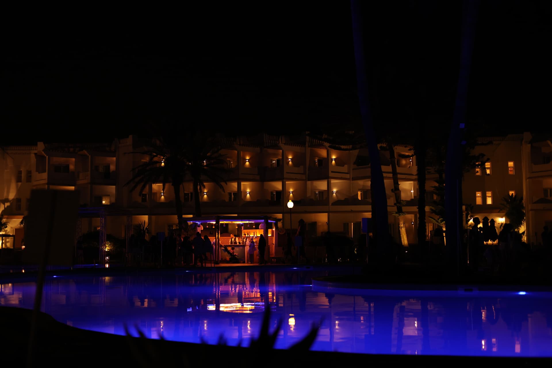 Evening exterior commercial photography of a hospitality venue with lit poolside bar