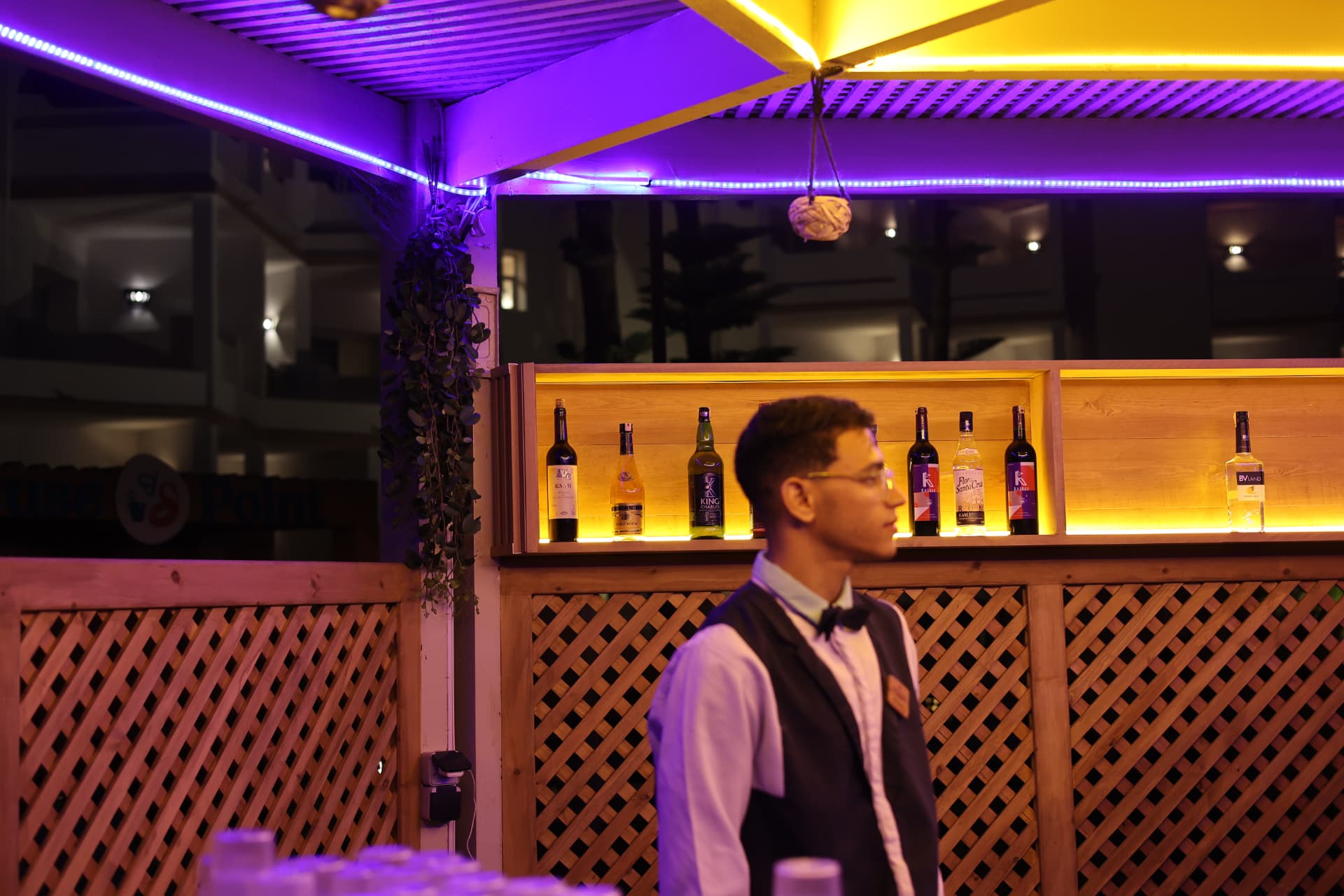 Bar area evening photography for hospitality venues in Somerset, bartender and backlit spirits shelf