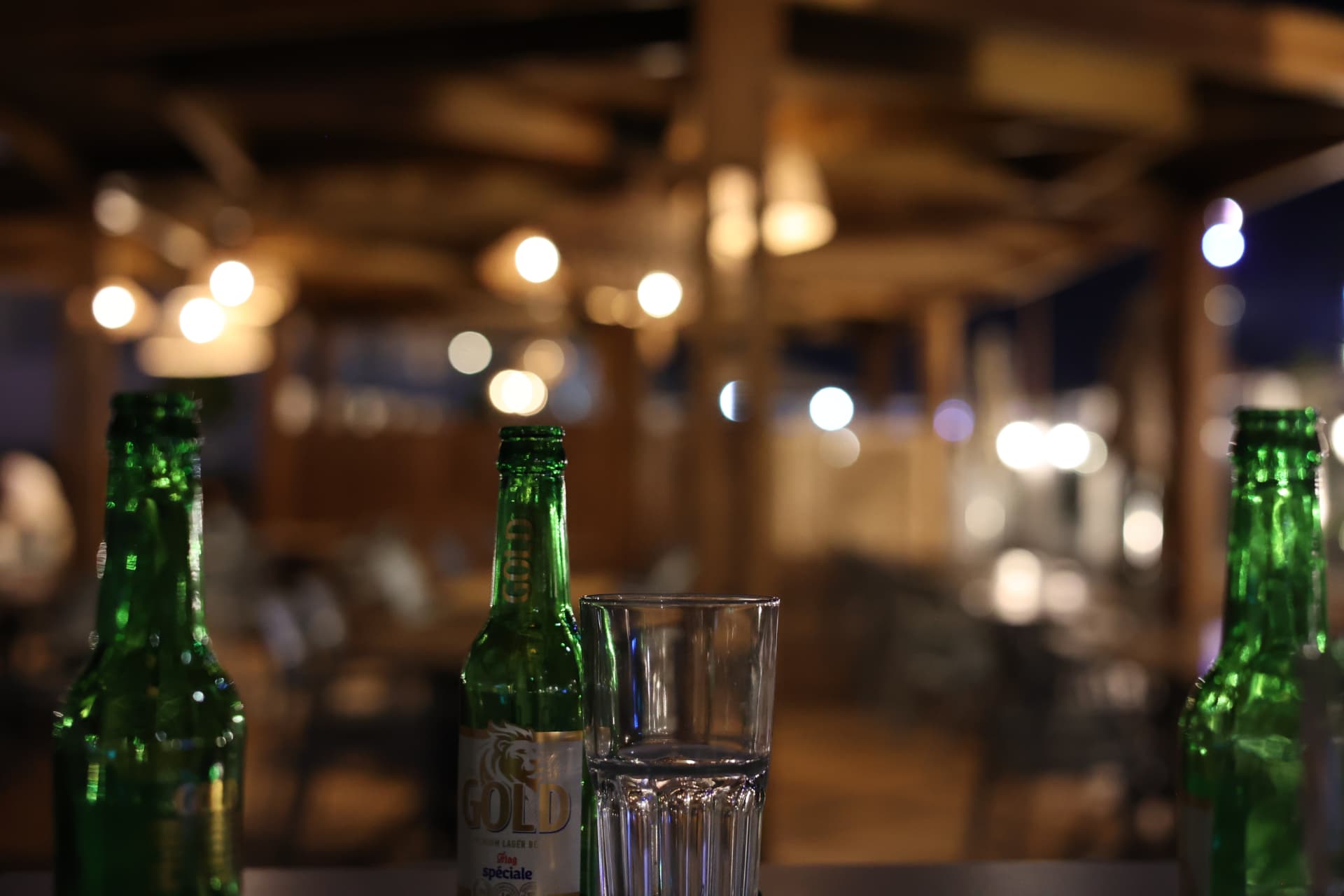 Restaurant table drinks detail photography Somerset, bottles and glass with warm bokeh interior lighting